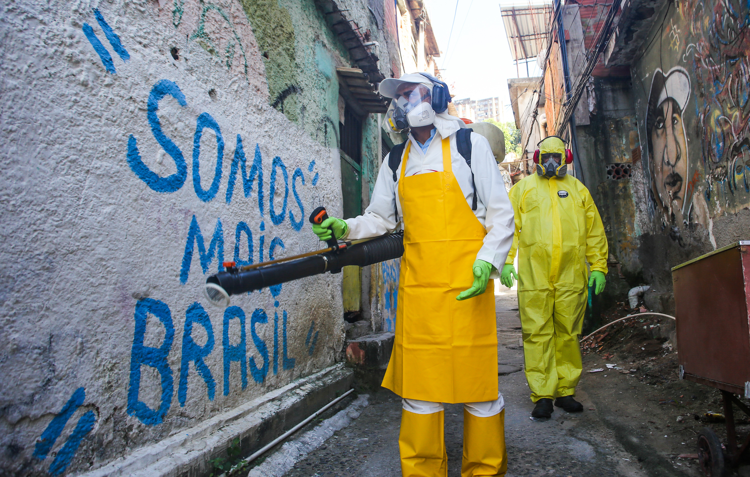 Agentes del departamento sanitario limpian calles y callejones de Vila Ipiranga Favela, en el barrio de Fonseca el 25 de marzo de 2020 en Niteroi, Brasil.