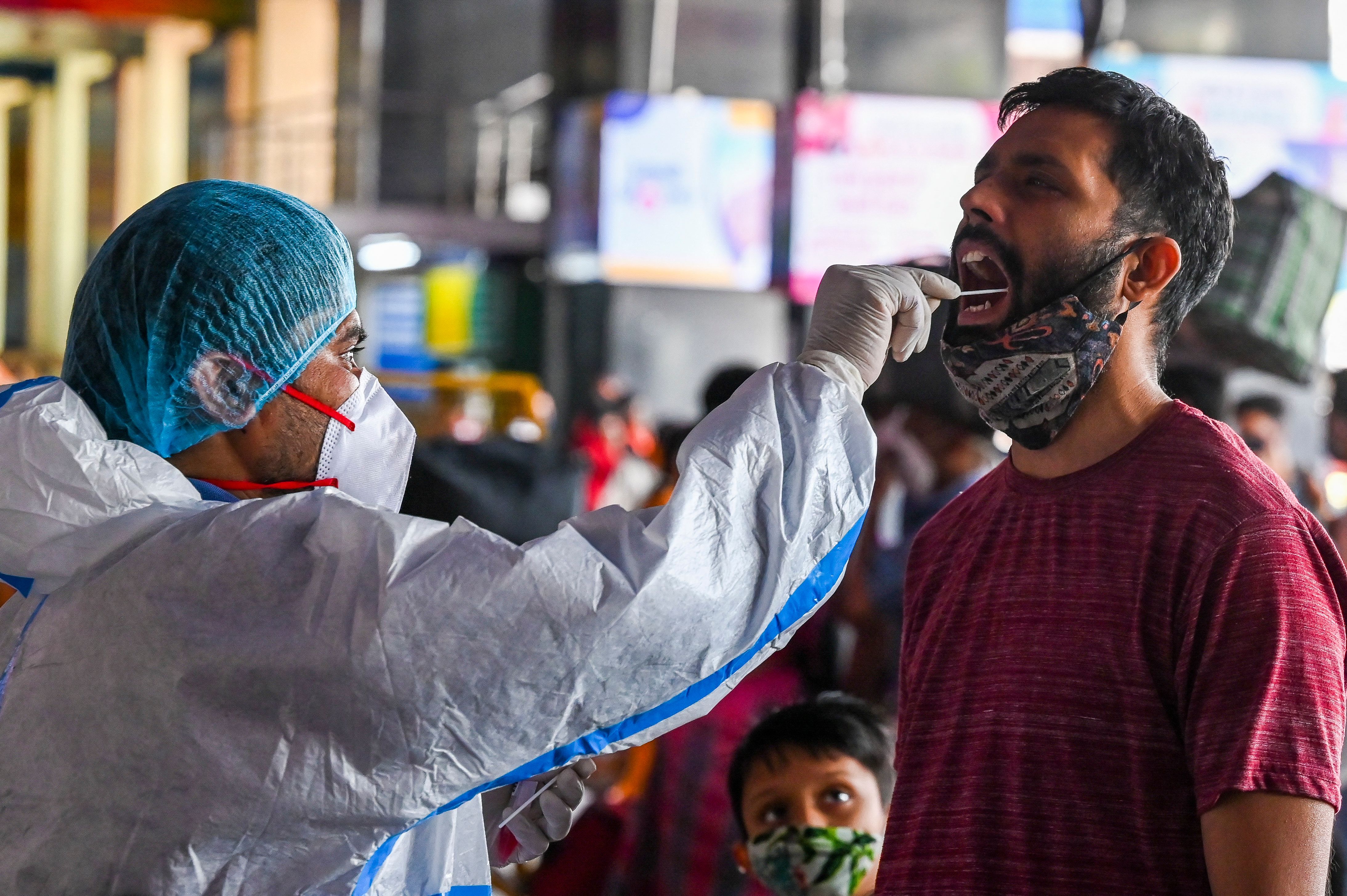 Un trabajador de la salud recolecta una muestra de hisopo de un pasajero para la prueba rápida de antígeno (RAT) para el coronavirus Covid-19 en una estación de tren en Nueva Delhi en el Match 25 de 2021