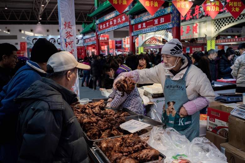 Esta imagen tomada el 15 de enero de 2020 muestra a un vendedor (R) vendiendo carne a clientes (L) en un mercado en Beijing. - La Organización Mundial de la Salud (OMS) dijo el 20 de enero que creía que una fuente animal era la "fuente principal" del brote, y las autoridades de la ciudad de Wuhan, en el centro de China, identificaron un mercado de mariscos en su ciudad como el centro de la epidemia. pero desde entonces China ha confirmado que había evidencia de que el virus ahora se transmite de persona a persona, sin ningún contacto con el mercado ahora cerrado. (