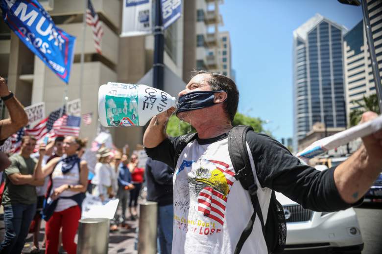Un manifestante vierte agua en su máscara mientras finge beber de una botella de lejía durante un mitin para reabrir California y contra las directivas de Stay-At-Home el 1 de mayo de 2020 en San Diego, California.