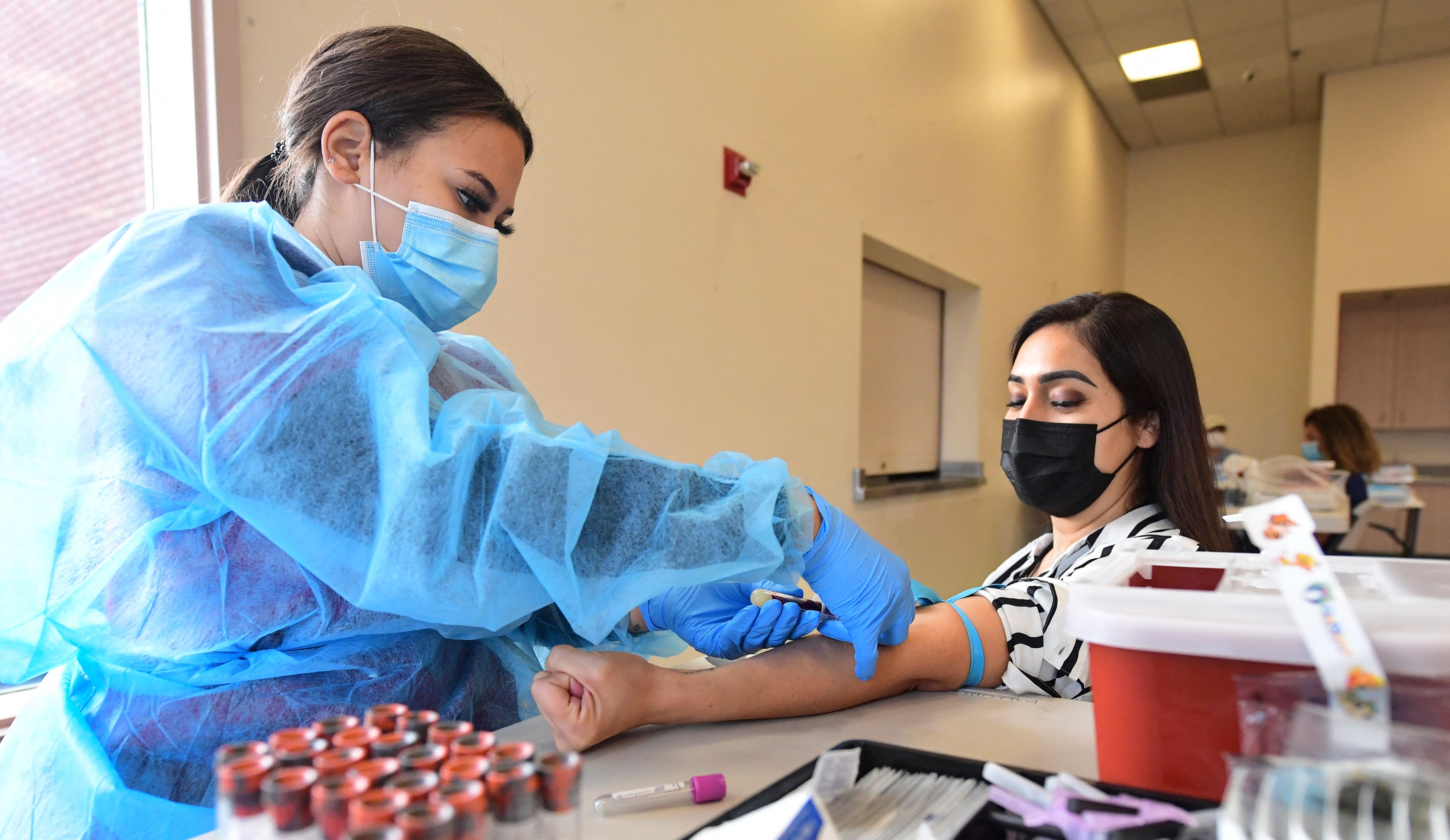 La flebotomista Briana Green extrae sangre de Maritza Nieves durante el nuevo uso de emergencia de la FDA y la prueba de anticuerpos IgG ll autorizada para personas vacunadas, que se ofrece de forma gratuita en Santa Fe Springs, California, el 21 de abril de 2021.