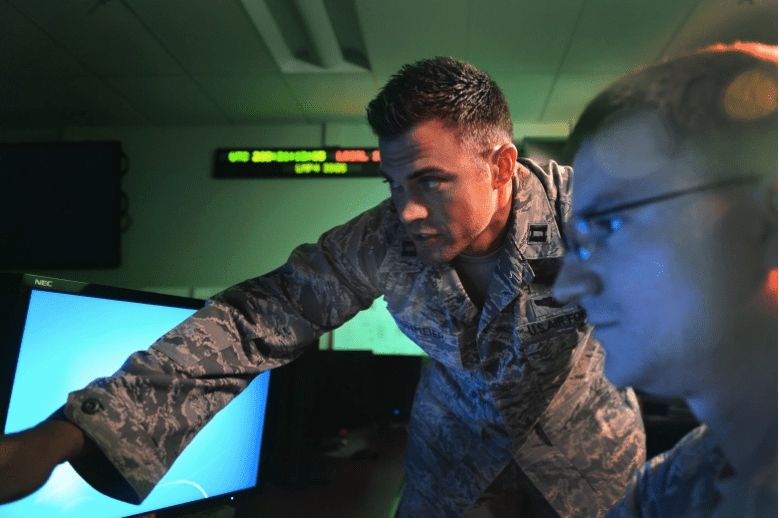 Matthew Lohmeier, entonces jefe de entrenamiento del Bloque 10 del Grupo de Operaciones 460, instruye a un aprendiz en el Entrenador espacial estandarizado el 22 de julio de 2015, en la Base de la Fuerza Aérea Buckley, Colorado.