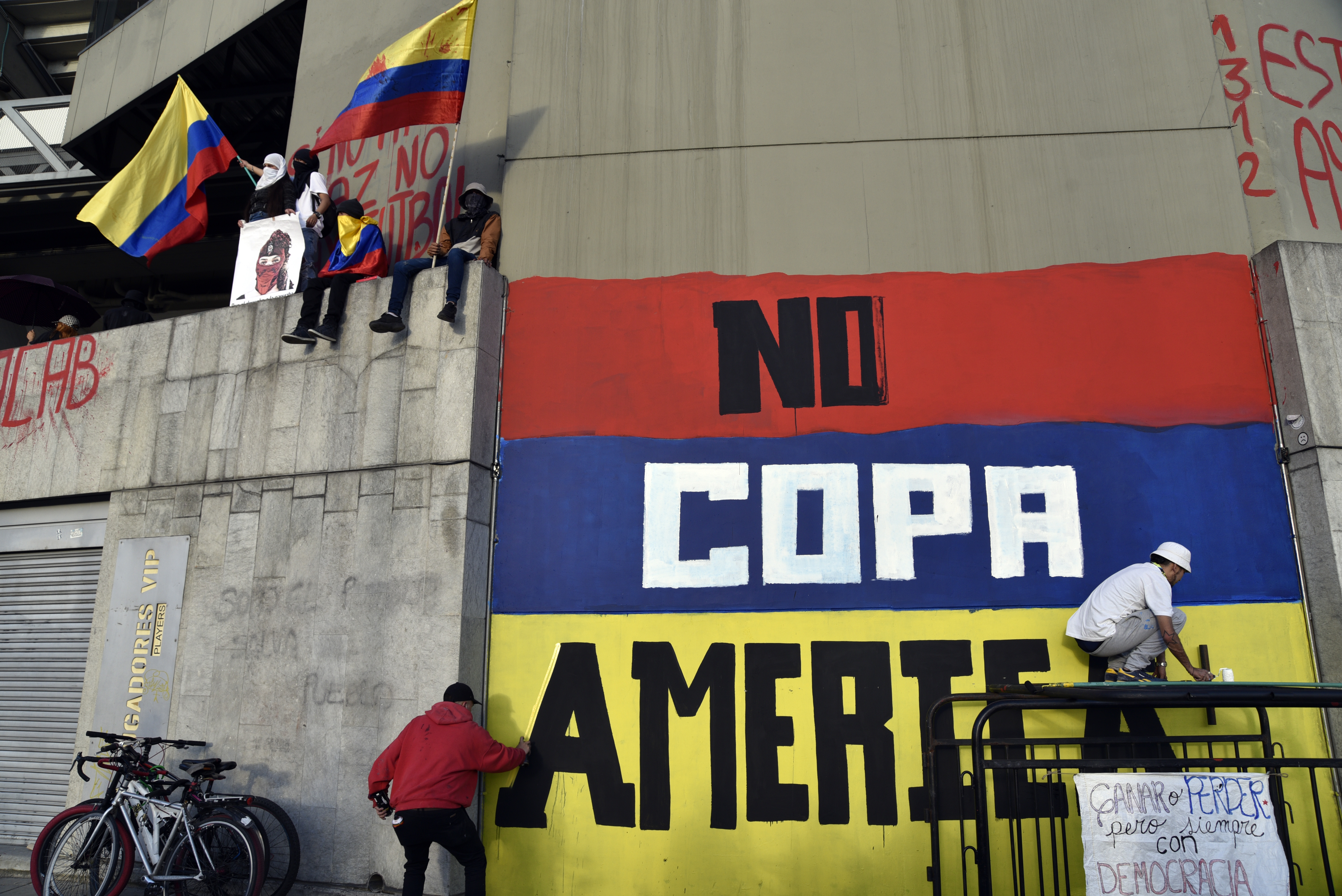 Artistas callejeros pintan un graffiti contra Colombia como anfitrión de la Copa América en una pared del Estadio Campin durante una protesta como parte de una huelga nacional el 19 de mayo de 2021 en Bogotá, Colombia.