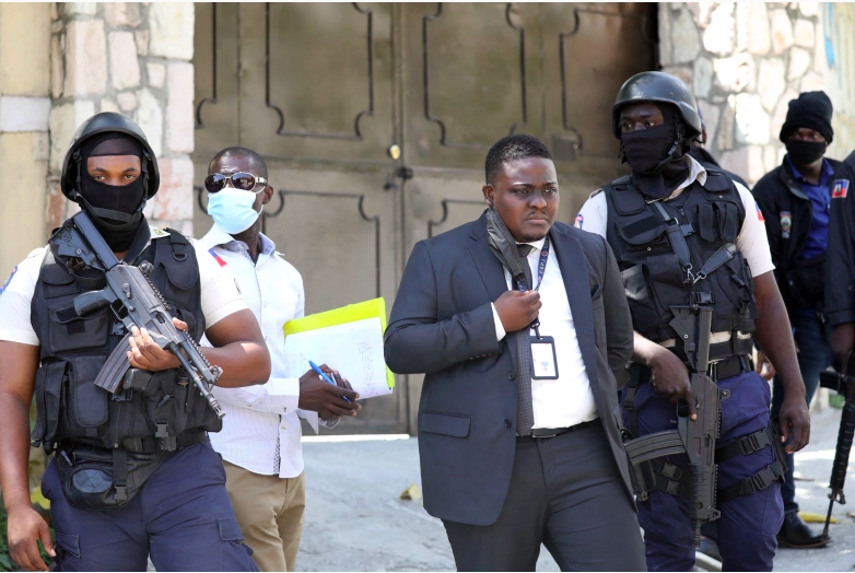 La policía de Direction Centrale de la Police Judiciaire (DCPJ) patrulla el área con forenses, mientras el juez Carl Henry Celestin (C) observa, fuera de la residencia presidencial el 7 de julio de 2021 en Puerto Príncipe, Haití.