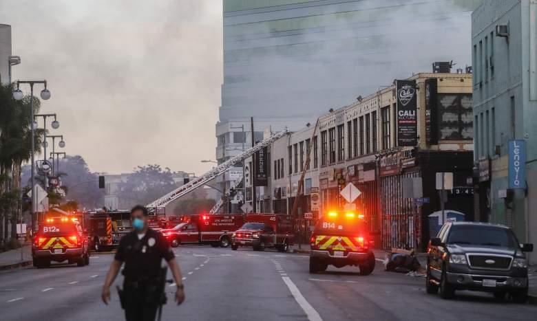 Un oficial de LAPD vigila un incendio de estructuras múltiples mientras los bomberos de LAFD trabajan después de una explosión el 16 de mayo de 2020 en los Ángeles, California.