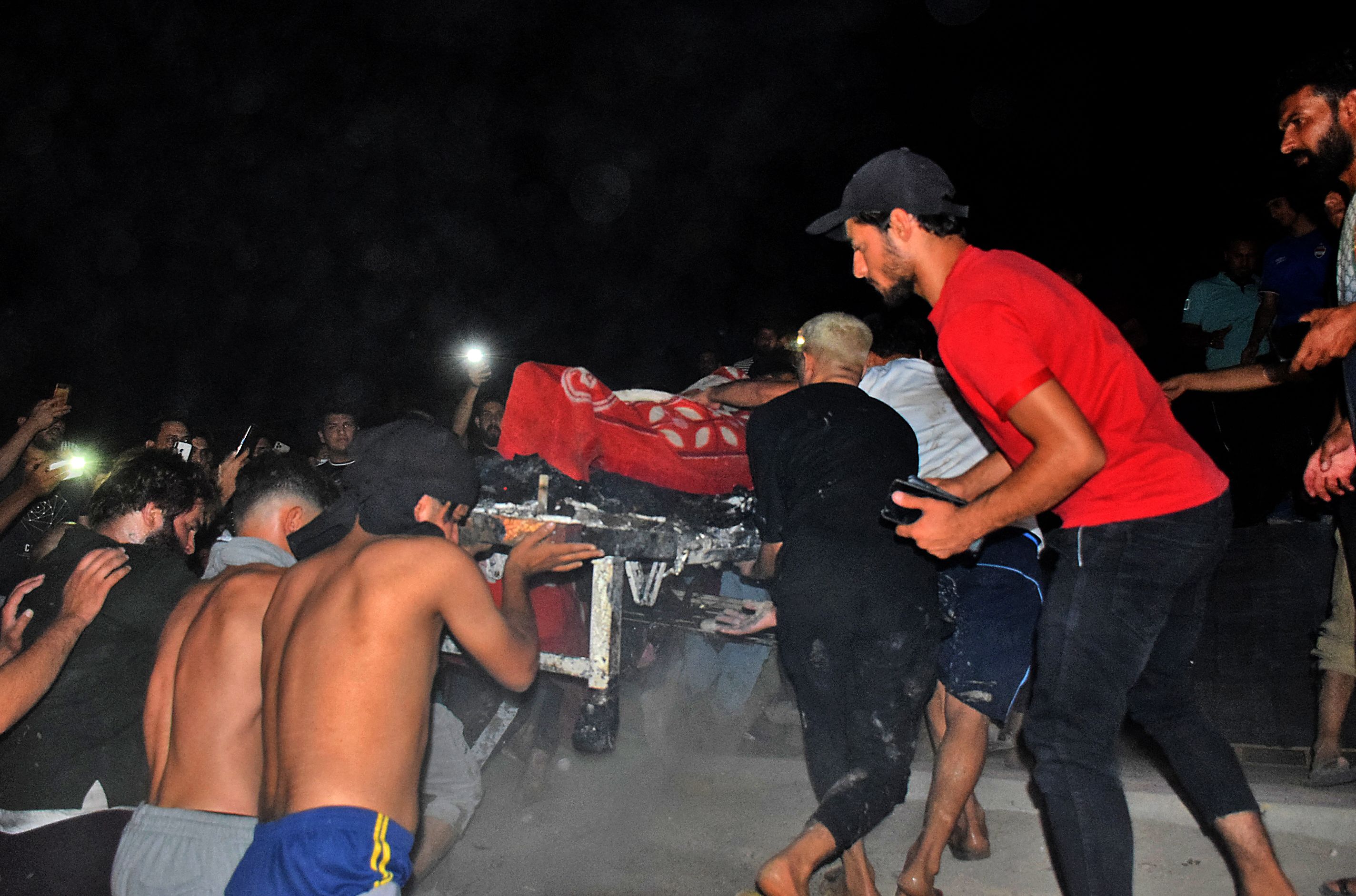 Las personas ayudan a evacuar a los pacientes mientras un incendio masivo envuelve la sala de aislamiento de coronavirus del hospital Al-Hussein en la ciudad de Nasiriyah, en el sur de Irak, a última hora del 12 de julio de 2021