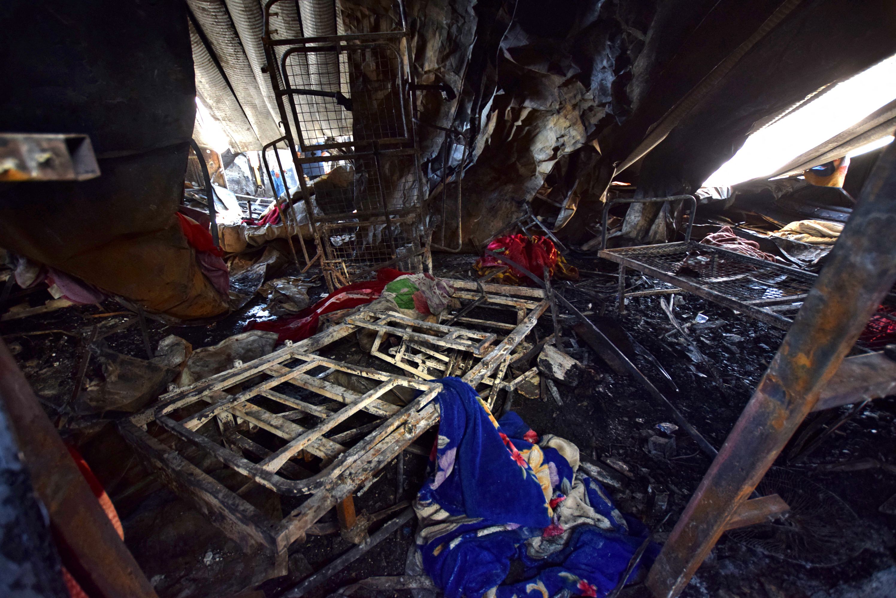 Las mantas están esparcidas entre las camas de hospital quemadas en la sala de aislamiento del coronavirus devastada del hospital Al-Hussein después de un incendio masivo durante la noche, en la ciudad de Nasiriyah, en el sur de Irak, el 13 de julio de 2021