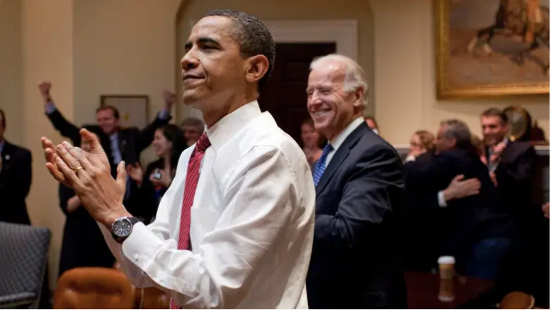 El presidente Barack Obama, el vicepresidente Joe Biden y el personal directivo aplauden en el Salón Roosevelt de la Casa Blanca, mientras la Cámara aprueba el proyecto de ley de reforma del sistema de salud.