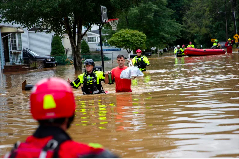 Los miembros de la Compañía de Bomberos Voluntarios de New Market ayudan a Doug, un residente del vecindario, durante un esfuerzo de evacuación luego de una inundación repentina, mientras la tormenta tropical Henri toca tierra en Helmetta, Nueva Jersey, el 22 de agosto de 2021.