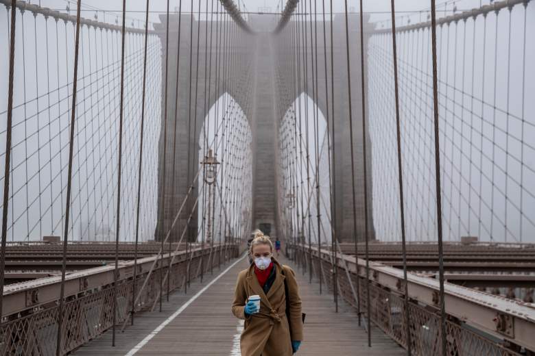 Una mujer con una máscara camina por el puente de Brooklyn en medio del brote de coronavirus (COVID-19)
