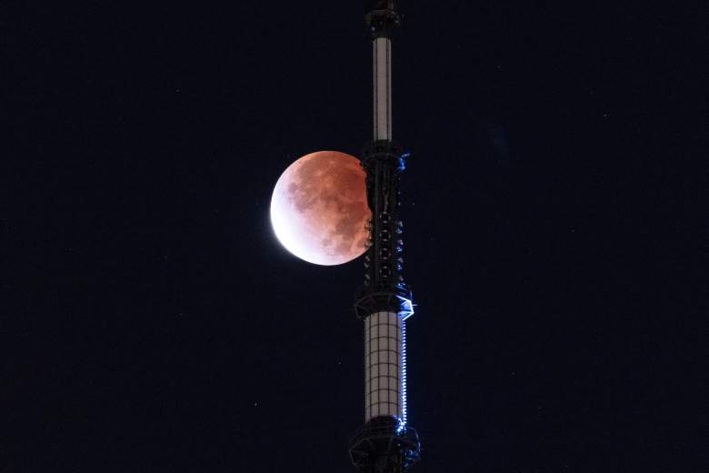 La luna se ve durante un eclipse lunar detrás del One World Trade Center en Nueva York a principios del 19 de noviembre de 2021