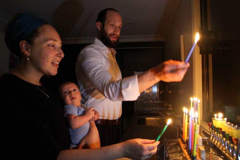 El rabino Phil Kaplan, Abra Kaplan y su hijo recién nacido Roee marcan Hanukkah con la iluminación de la menorá en casa el 15 de diciembre de 2020 en Sydney, Australia.