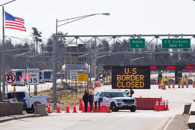 Los funcionarios de aduanas de EE. UU. Junto a un letrero que dice que la frontera de EE. UU.