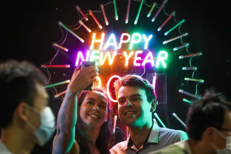 Gente vista tomando su foto frente a un letrero de neón de Feliz Año Nuevo