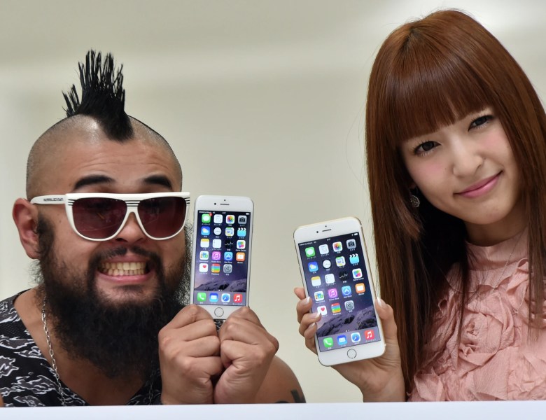 El primer cliente del teléfono inteligente más nuevo de Apple, el iPhone 6, el Sr. Butch (L) y la cantante japonesa Sayaka Kanda exhiben el iPhone 6 (L) y el iPhone 6 Plus en la tienda de teléfonos móviles Softbank en Tokio el 19 de septiembre de 2014.