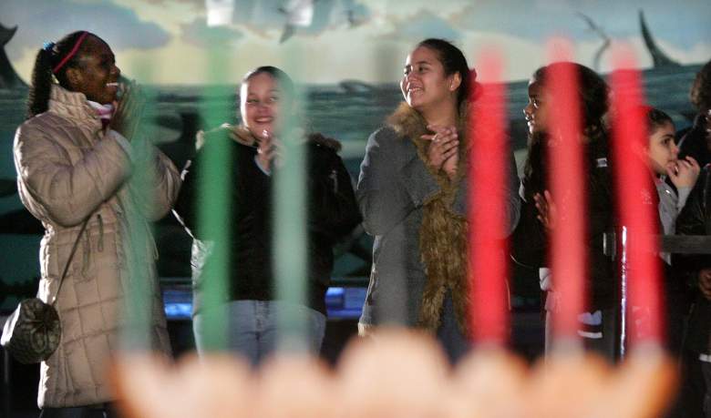 Los niños aplauden detrás de un candelabro tradicional "kinara" mientras los músicos interpretan música africana durante una vista previa para la prensa del festival "Kwanzaa 2004: We Are Family" en el Museo Americano de Historia Natural el 22 de diciembre de 2004 en la ciudad de Nueva York .