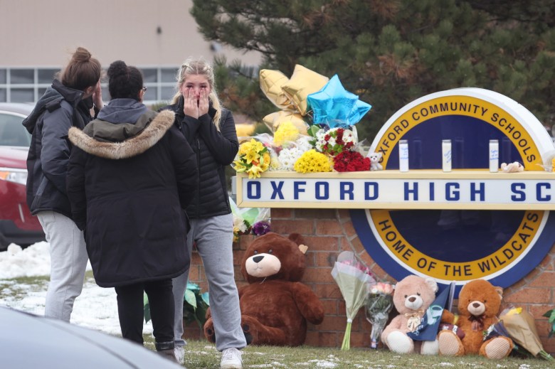 Los dolientes reaccionan cuando visitan un memorial improvisado fuera de Oxford High School el 1 de diciembre de 2021 en Oxford, Michigan.