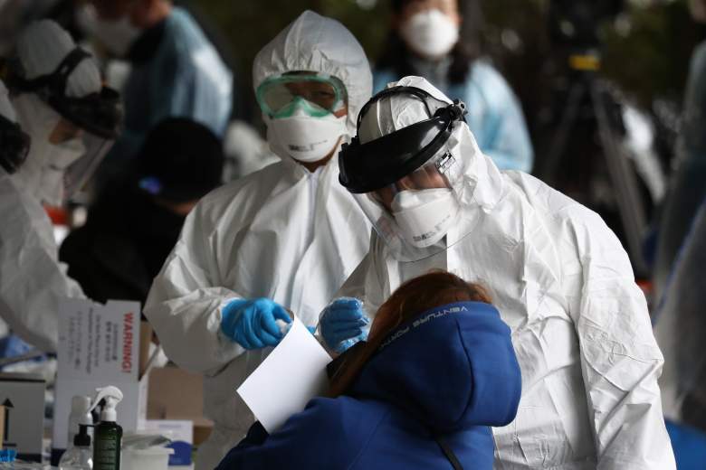 El personal médico, con equipo de protección, toma muestras de personas en un edificio donde se confirmó que 46 personas tenían el coronavirus