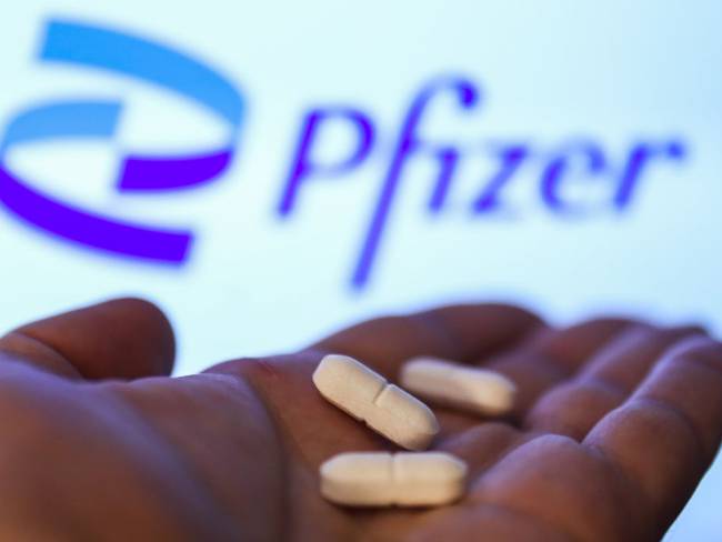 En esta foto de ilustración tomada en Cracovia, Polonia, el 27 de abril de 2021, se ven píldoras medicinales con el logotipo de Pfizer en una pantalla en el fondo.