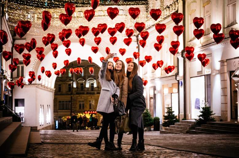 Las mujeres posan para una selfie bajo globos en forma de corazón que se muestran en la víspera del Día de San Valentín