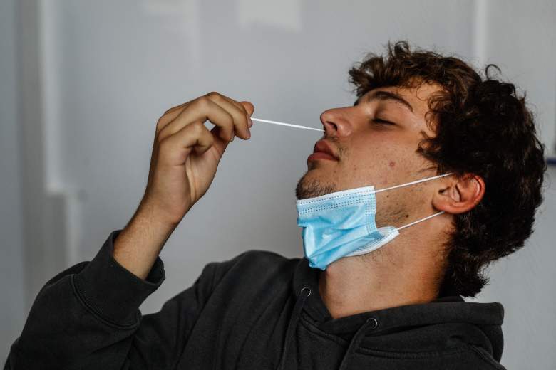Un hombre toma su propia muestra de hisopo nasal para hacer una autoprueba de Covid-19