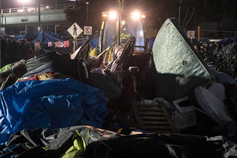 Migrantes se reúnen con sus pertenencias junto a un autobús mientras las autoridades desmantelan un campamento improvisado frente al puerto de cruce de El Chaparral en Tijuana, estado de Baja California, México, cerca de la frontera con EE. UU., el 6 de enero de 2022.