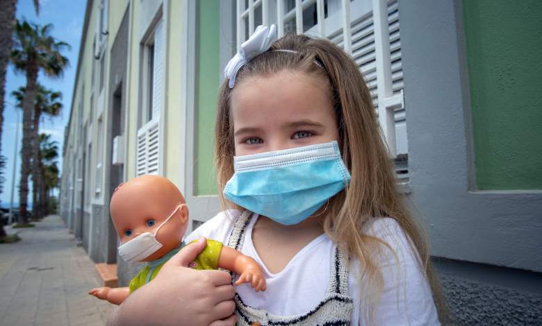 Naidelin, de 5 años, y su muñeca posan con una mascarilla en la calle de Santa Cruz, en la isla canaria de Tenerife, el 26 de abril de 2020 durante un confinamiento nacional para evitar la propagación de la enfermedad COVID-19.
