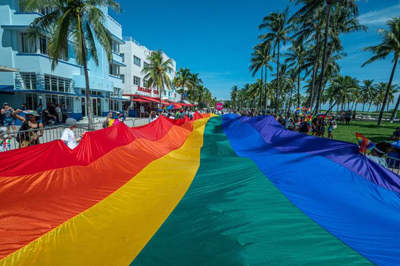 Una enorme bandera multicolor ondea sobre Ocean Drive mientras la gente participa en el Desfile del Orgullo, durante el Festival del Orgullo de Miami Beach, en Lummus Park, South Beach, Florida, el 19 de septiembre de 2021.