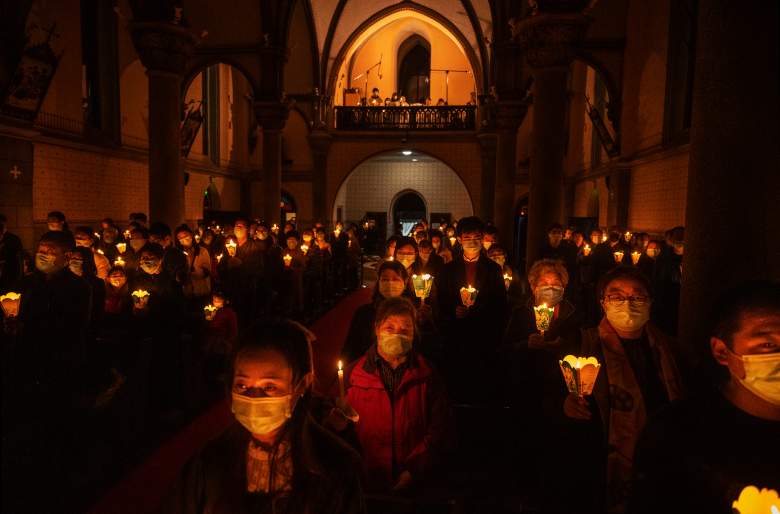 Fieles católicos chinos sostienen velas como parte del fuego sagrado en una misa de Pascua en una iglesia católica el 3 de abril de 2021 en Beijing, China.