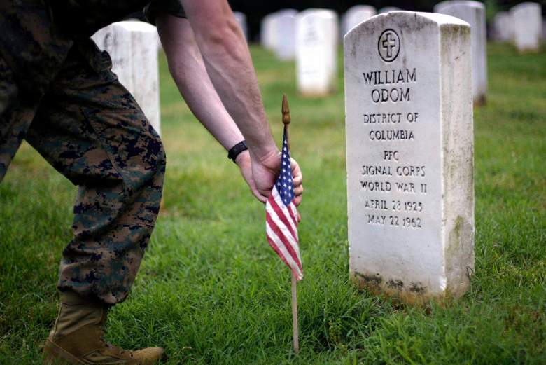 Un destacamento de la Marina de los EE. UU. de Annapolis, Maryland, ayuda a la 3.ª Guardia Vieja de Infantería a colocar unas 290.000 banderas en cada lápida en preparación para el Día de los Caídos el 27 de mayo de 2004 en el Cementerio Nacional de Arlington en Arlington, Virginia.