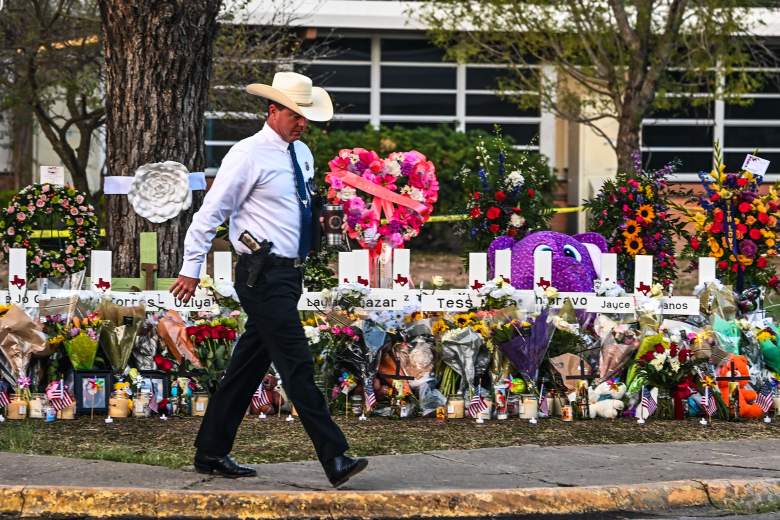 Un oficial de policía pasa frente a un monumento improvisado para las víctimas del tiroteo afuera de la Escuela Primaria Robb en Uvalde, Texas, el 27 de mayo de 2022.