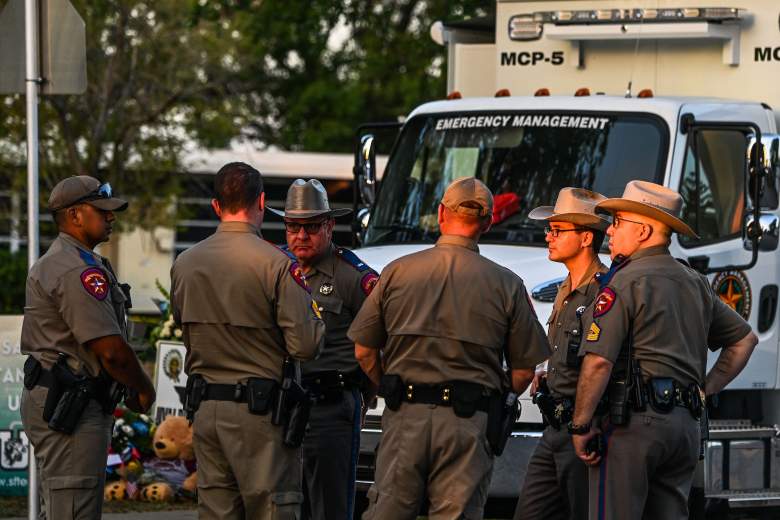Oficiales de policía hablan cerca de un monumento improvisado para las víctimas del tiroteo afuera de la Escuela Primaria Robb en Uvalde, Texas, el 27 de mayo de 2022.