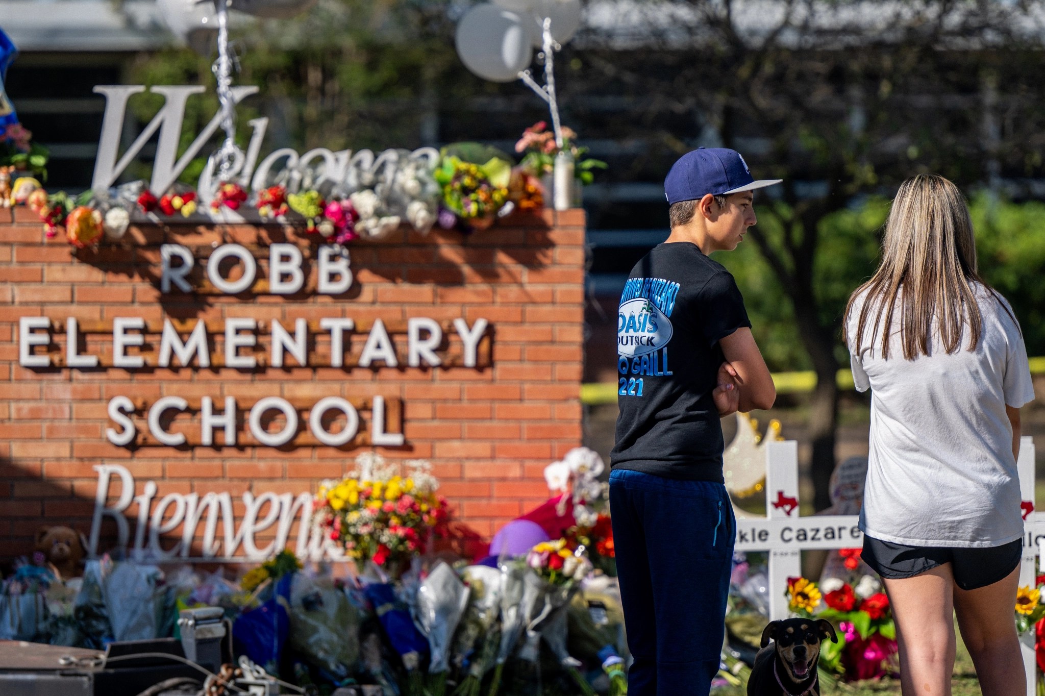 Adultos jóvenes observan un monumento en la Escuela Primaria Robb luego de un tiroteo masivo el 26 de mayo de 2022 en Uvalde, Texas.