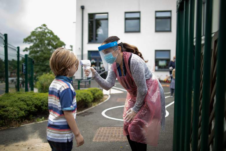 Un miembro del personal que usa equipo de protección personal (EPP) toma la temperatura de un niño en la escuela Shortland de la Academia Harris el 4 de junio de 2020 en Londres, Inglaterra.