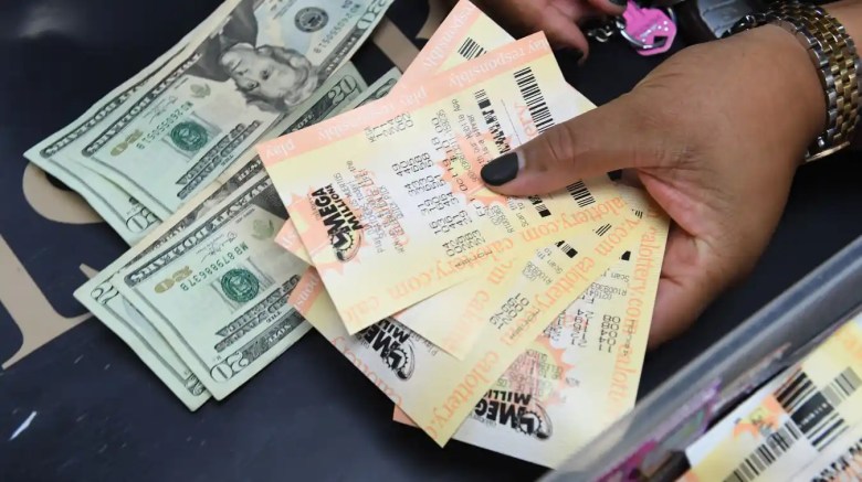 Una mujer muestra sus boletos de Mega Millions horas antes del sorteo del premio mayor de USD 1000 millones.