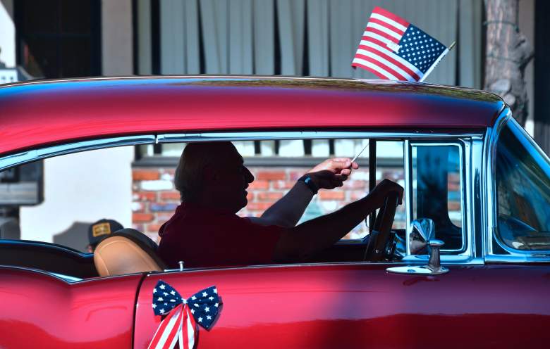 Un hombre ondea la bandera de los EE. UU. mientras conduce su automóvil clásico durante un desfile del 4 de julio en San Gabriel, California, el 4 de julio de 2018